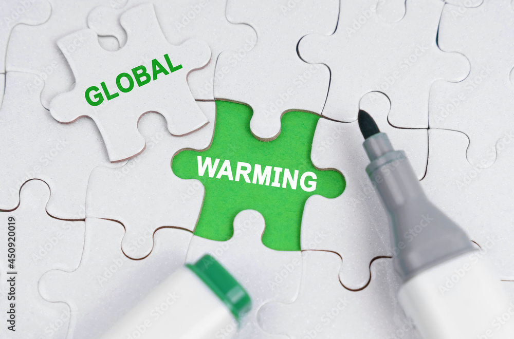 Fototapete white puzzles lie on a green background, in place of an open puzzle it is written - global warming