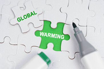 White puzzles lie on a green background, in place of an open puzzle it is written - Global Warming