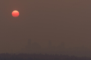 Heavy wildfire smoke surrounds Seattle with orange sun at sunset
