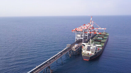 Bulk container ship unloads coal in the port of power station.