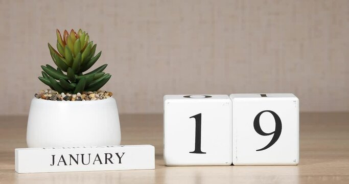 Wooden calendar with an important event for January 19, a woman's hand sets the date on the calendar. Winter season.