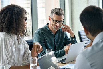 Diverse international executive business people working on project at boardroom meeting table using...