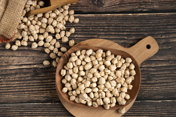 Wooden plate with chickpeas on wooden table. Overhead view
