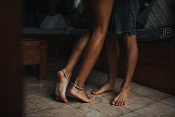 Snapshot of female and male tanned legs standing on marble tile