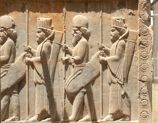 Soldiers of historical empire with weapon in hands. Stone bas-relief in ancient city Persepolis,...