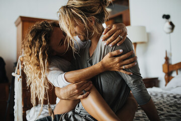 Long-haired man strokes the knee of his girlfriend who tenderly embraces him by neck