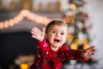 A little boy in Christmas pajamas smiles