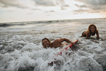 Woman and her boyfriend surfing in ocean