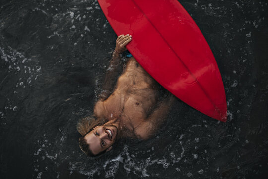 Man Swims With His Red Surfboard