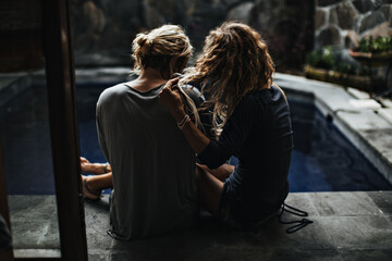 Curly girl in T-shirt touches her hair and hugs her boyfriend near pool