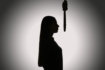 Silhouette of woman with rope noose on light background