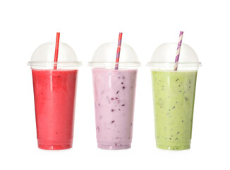 Different smoothies with straws in plastic cups on white background