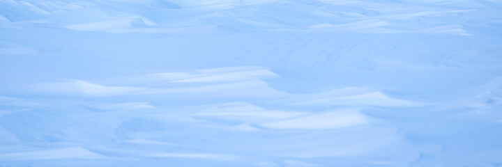 Beautiful winter background with snowy ground. Natural snow texture. Wind sculpted patterns on snow surface. Arctic, Polar region.