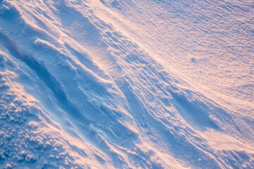 Fototapeta premium Beautiful winter background with snowy ground. Natural snow texture. Wind sculpted patterns on snow surface.