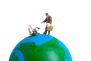 Miniature people toy figure photography. Charity day concepts. A philanthropic businessman giving money to beggar above earth globe. Isolated on white background. Image photo - obrazy, fototapety, plakaty