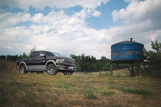 Brno, Czech Republic - June 28 2014: Dodge RAM 1500 standing in a meadow next to an old rusty water tank.
