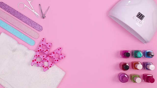 Manicure nail set with uv lamp and accessories appear on pink theme. Stop motion flat lay