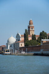 Fototapeta na wymiar An old church with bell tower and domes on canal in Venice, Italy, 2019