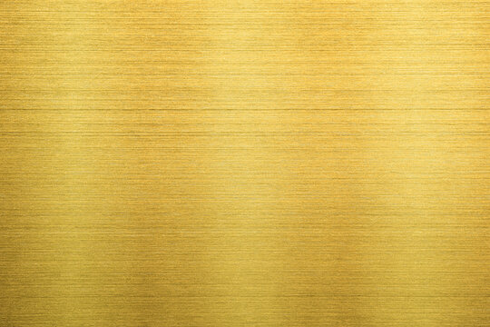 Shiny gold polished metal background texture of brushed stainless steel plate with the reflection of light.