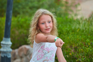 portrait of baby girl on background of greenery. Girl posing against background of summer greenery. Portrait of little girl