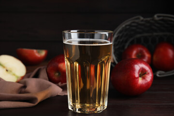Glass of delicious cider and ripe red apples on wooden table