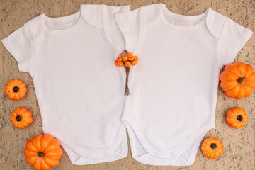 Two white baby bodysuit mockup with halloween decor on gold background. Autumn, halloween and...