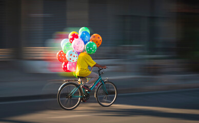 Motion blur of Asian balloon seller riding bicycle on the street in evening time