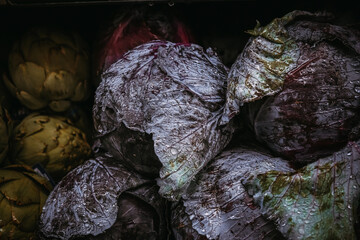 Fototapeta na wymiar Raw vegetables purple cabbage and artichoke . Closeup selective phocus. Dark toning.