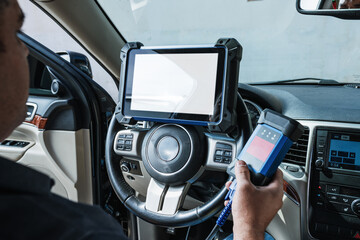 Car diagnostic. Technical inspection, car electronics. A Latin man holds a digitizing device.