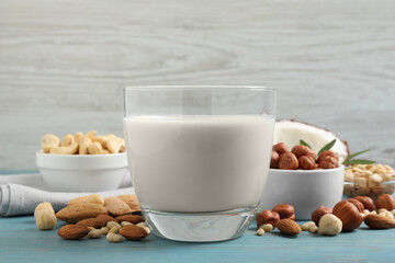 Vegan milk and different nuts on light blue wooden table