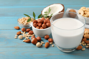 Vegan milk and different nuts on light blue wooden table. Space for text