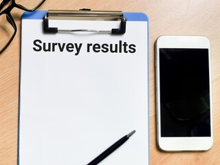 Text survey results on clipboard paper with a pen,eye glasses and smartphone.