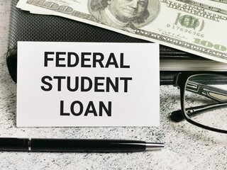 White card with text federal student loan with a pen and fake money.