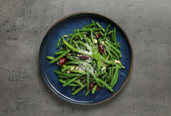 Plate of tasty salad with green beans on grey table, top view