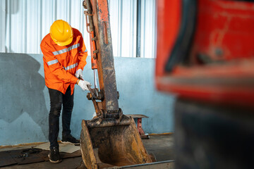 A technician holding a tool for maintenance or excavator at maintenance center, Heavy Duty...