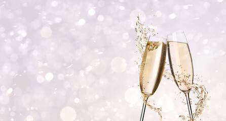Glasses with sparkling wine and splashes on light background, space for text. Banner design