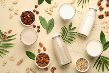 Obraz na płótnie Canvas Different vegan milks and ingredients on beige background, flat lay