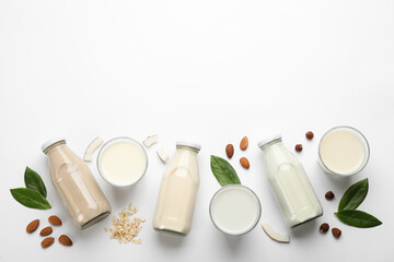 Fototapeta na wymiar Different vegan milks and ingredients on white background, flat lay. Space for text
