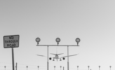 Jet aircraft on final approach over navigation lights at the end of the runway at an International Airport - Black and White