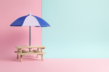 Small wooden holder with toy umbrella on color background, space for text