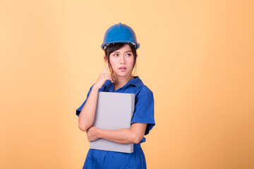 Young Asian female engineer working deliberately isolated on yellow background.	
