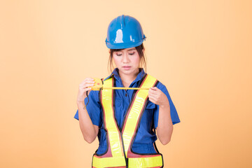 Portrait woman mechanic checking on yellow background