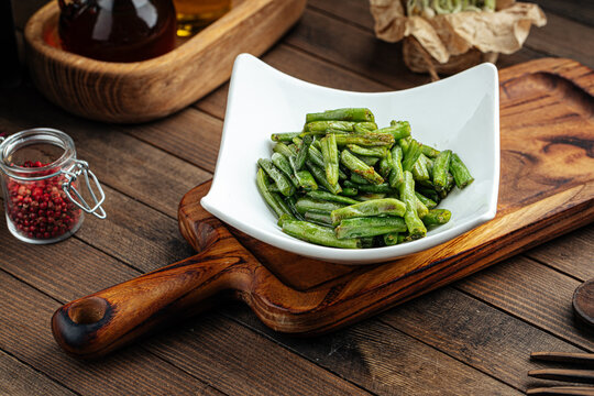 Plate of fried green string beans garnish on a wooden background