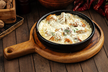 Georgian chkmeruli chicken dish with cream sauce on a wooden background