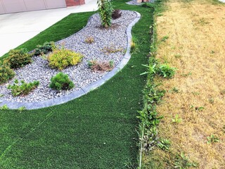 A comparison photo of a  artificial synthetic lawn beside a real natural grass in the summer.  The...