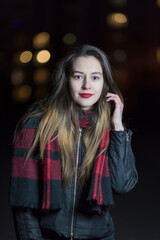 Portrait of a young beautiful dark-haired girl in the night city, close-up.