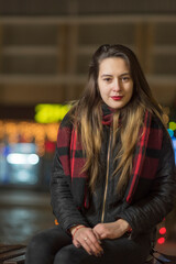 Portrait of a young beautiful dark-haired girl in the night city, close-up.