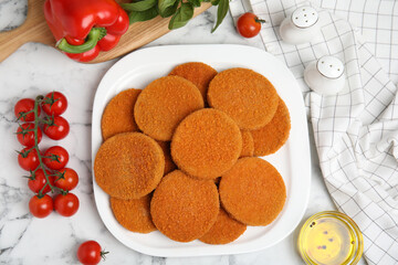 Delicious fried breaded cutlets, spices and vegetables on white marble table, flat lay