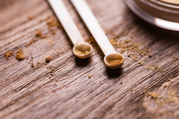 Mineral powder with a spoon dispenser for make-up on wooden background