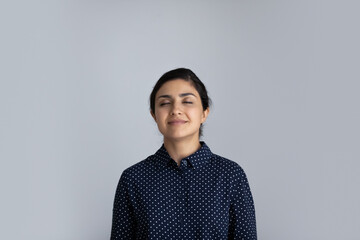 Happy millennial Indian woman isolated on grey studio background breathe fresh ventilated condition...